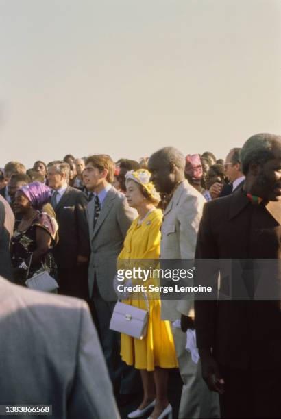 British Royals Prince Andrew and his mother, Queen Elizabeth II, wearing a yellow dress with a yellow-and-white hat, and Zambian politician Kenneth...