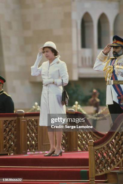 British Royal Queen Elizabeth ll, wearing a white coat and a white safari-style hat, alongside Sultan of Oman Qaboos bin Said at welcoming ceremony...
