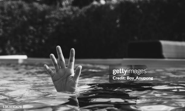 hand of person drowing in swimming pool. black and white tone. - drowning victim photos ストックフォトと画像