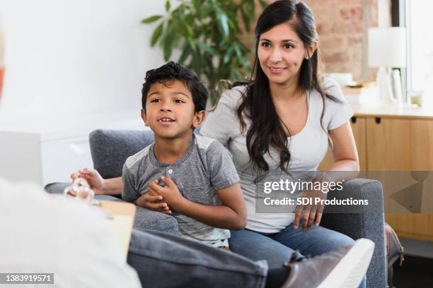 mid adult mom smiles as son listens to therapist - child psychologist stock pictures, royalty-free photos & images