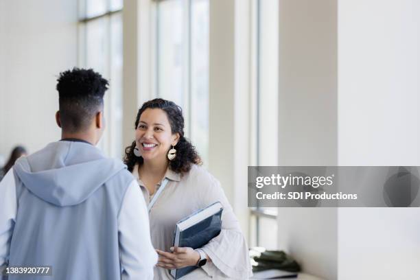 unrecognizable teen boy talks to smiling female teacher - satisfied students stockfoto's en -beelden