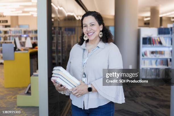 dedicated female librarian carries books to re-shelve - bibliotecário imagens e fotografias de stock