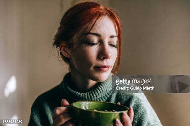 woman drinking green tea out of a green cup. - young woman stock-fotos und bilder