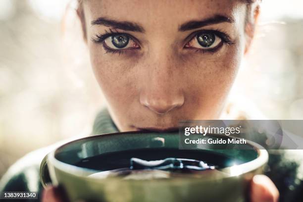 portrait of woman with big green eyes drinking tea. - woman drinking tea stock-fotos und bilder