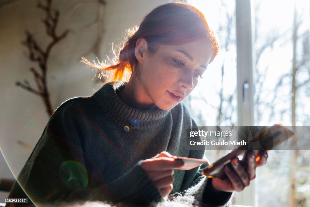 Woman shopping online with laptop and credit card on hand.