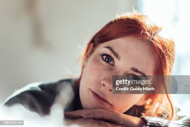 portrait of a thoughtful looking young woman at home. - red head stock-fotos und bilder