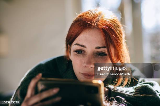 smiling woman watching movie with her smart phone. - depth of field imagens e fotografias de stock