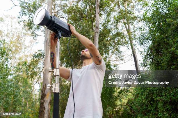 cameraman at work setting spotlights on movie set (outdoors) - reportage foto e immagini stock