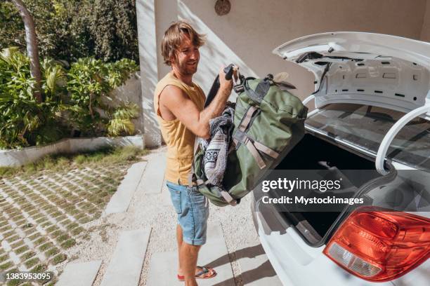 male packing for a trip loading his baggage onto a car trunk - possession stock pictures, royalty-free photos & images