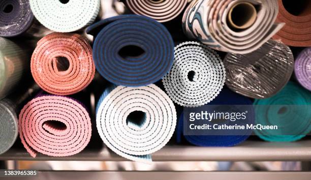 stack of rolled yoga & exercise mats on retail shelf - rolled up yoga mat stock pictures, royalty-free photos & images