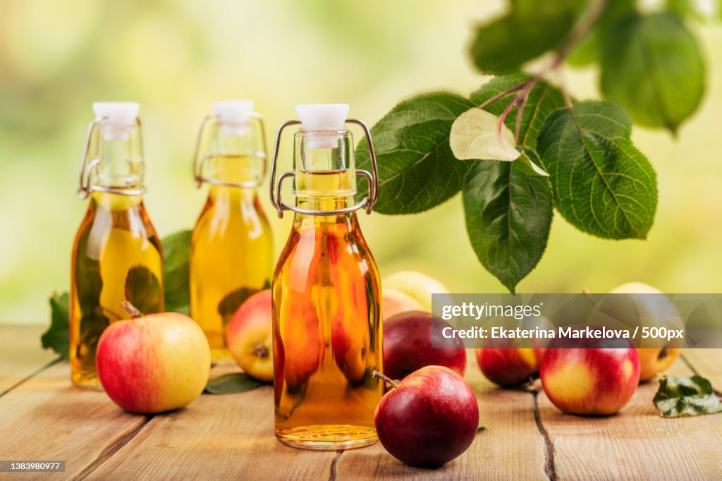 Close-up of apple vinegar with bottle and apple on table