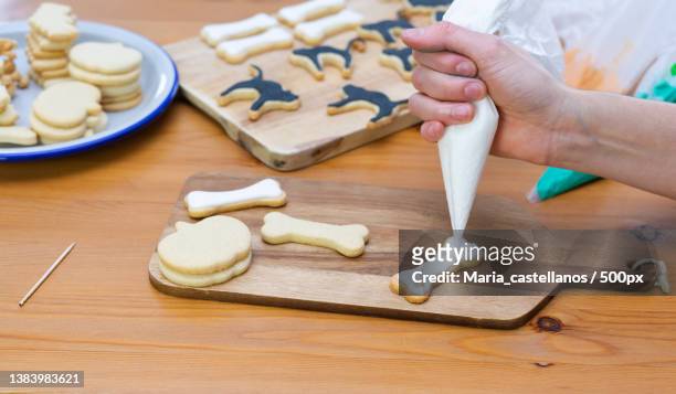 womans hand decorating cookies for halloween with piping bag - maria castellanos stock pictures, royalty-free photos & images