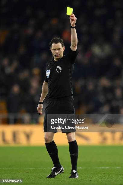 Referee Darren England awards Samir of Watford, not pictured, a yellow card during the Premier League match between Wolverhampton Wanderers and...