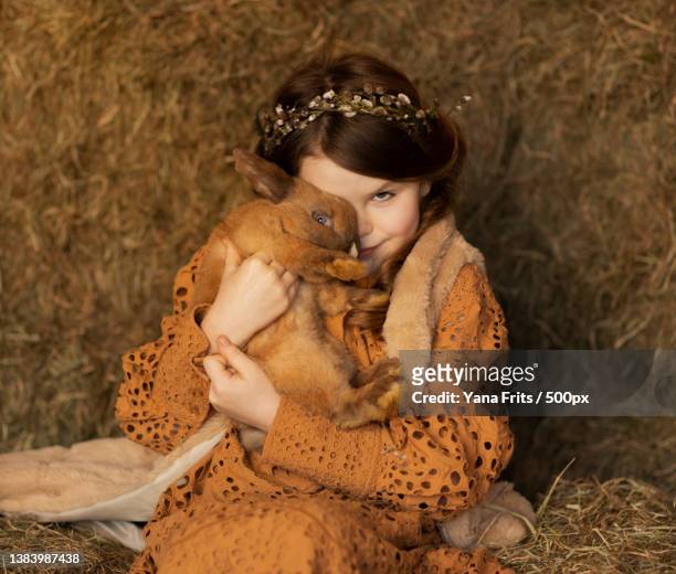 portrait of young woman with dog sitting on field,germany - dog easter stock-fotos und bilder