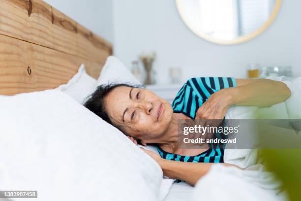 mujer con dolor de garganta acostada en la cama - acostado de lado fotografías e imágenes de stock