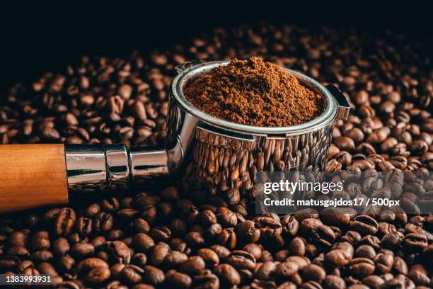 close-up of coffee beans with roasted beans on table,prague,czech republic - geroosterde koffieboon stockfoto's en -beelden