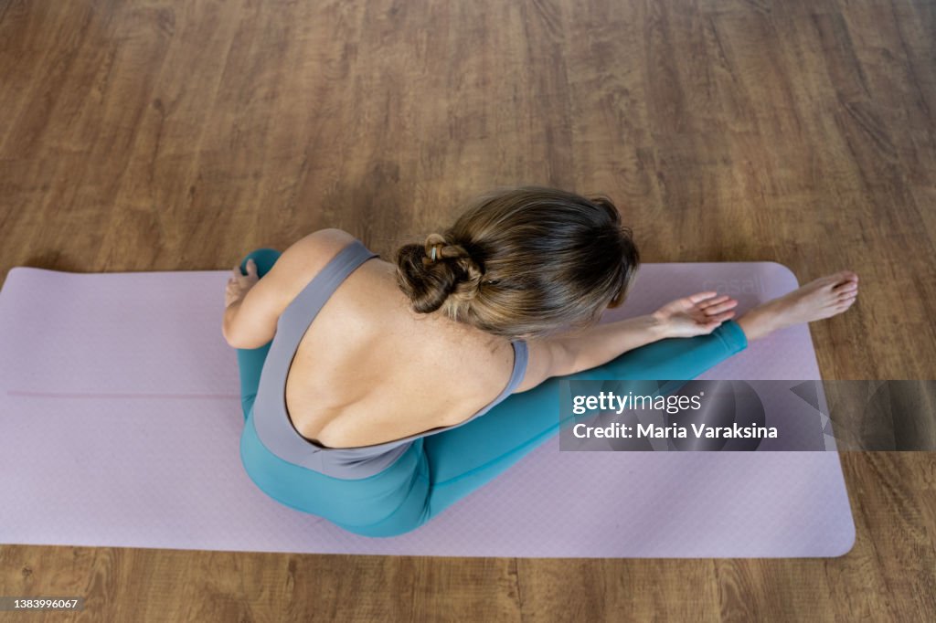 Middleaged Woman Practicing Yoga On A Powder Pink Yoga Mat On A Wooden  Floor At Home High-Res Stock Photo - Getty Images