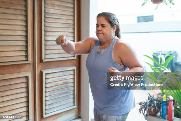 woman doing kickboxing cardio workout at home - glory kickboxing stockfoto's en -beelden