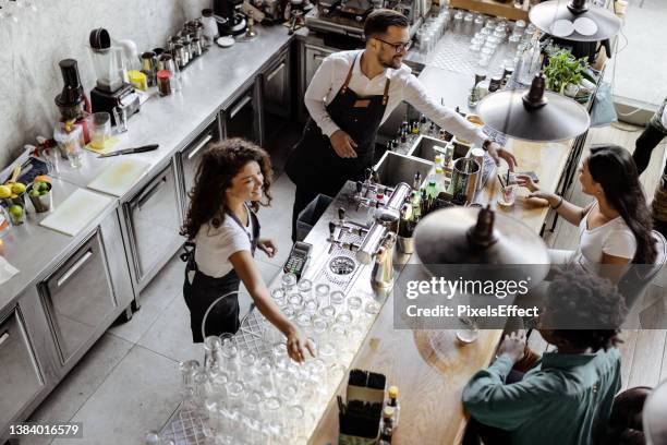 barista-mann und -frau, die in einem café arbeiten und mit einem kunden sprechen - women serving coffee stock-fotos und bilder