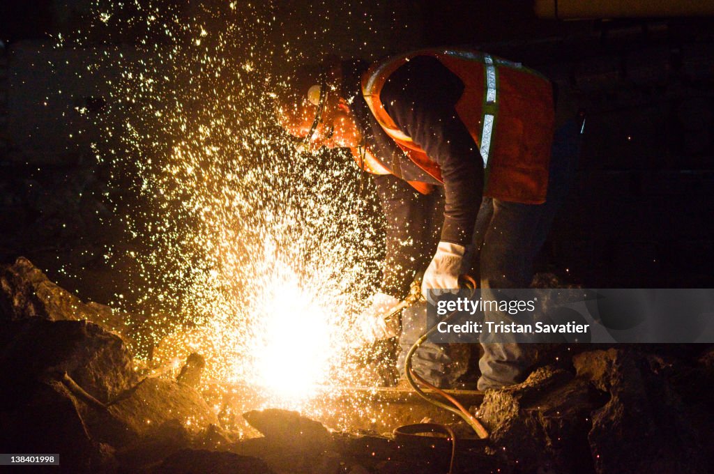 Welder cutting rail with oxy-acetylene torch