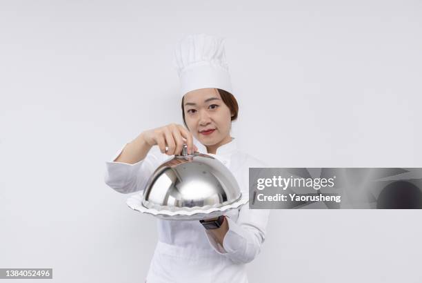 asian female chef wearing a chef's hat and carrying a domed tray and holding a empty plate. advertisement material - domed tray stock pictures, royalty-free photos & images