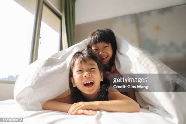 two asian girls playing quilt on the bed. - family on bed stock pictures, royalty-free photos & images