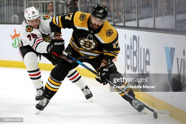 Alec Regula of the Chicago Blackhawks defends Nick Foligno of the Boston Bruins during the first period at TD Garden on March 10, 2022 in Boston,...