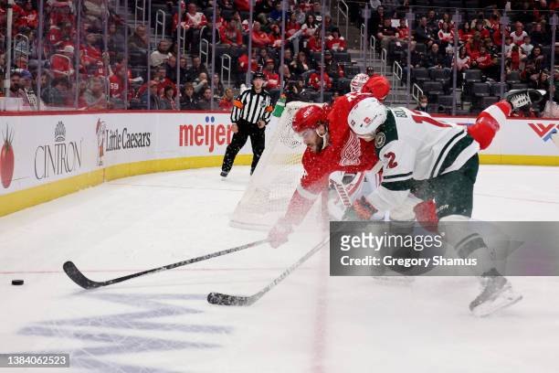 Michael Rasmussen of the Detroit Red Wings dives for the puck past Matt Boldy of the Minnesota Wild during the first period at Little Caesars Arena...