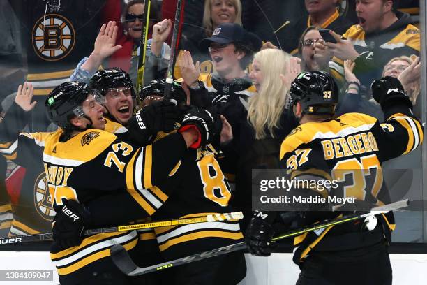 David Pastrnak of the Boston Bruins celebrates with Patrice Bergeron, Mike Reilly, and Charlie McAvoy after scoring the game winning goal against the...