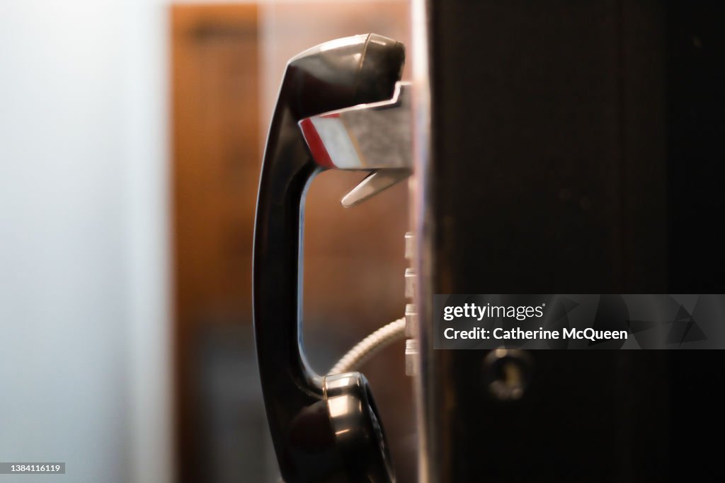 Side profile view of old-fashioned public pay phone in school building