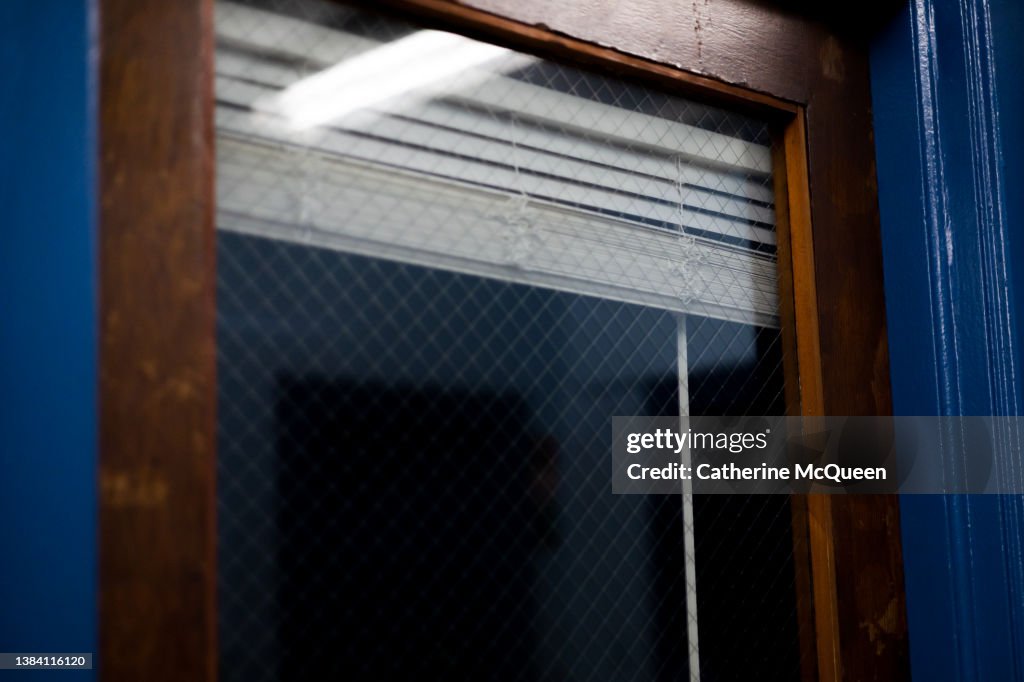 Closed door in school hall with window with blinds partially drawn