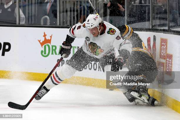 Jake McCabe of the Chicago Blackhawks checks David Pastrnak of the Boston Bruins into the boards during the third period at TD Garden on March 10,...