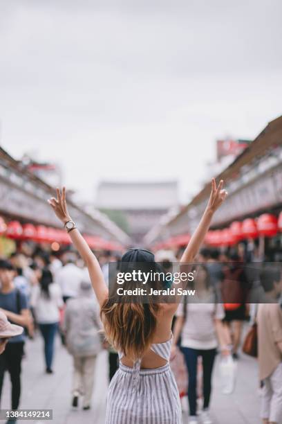 backview of young hipster woman on the streets of japan with her arms out raised - japan tourism stock pictures, royalty-free photos & images