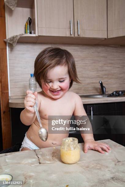 cheerful little girl eating puree from jar - baby spielt mit essen stock-fotos und bilder