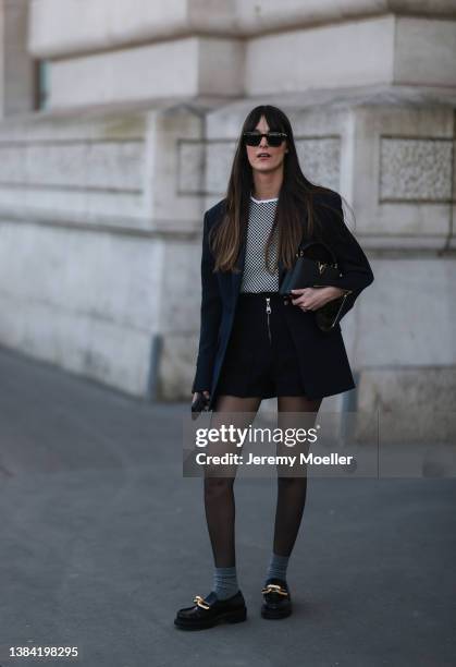 Leia Sfez seen wearing a black skirt with zipper, navy blazer, black pants, sheer tights, grey socks, black loafers with golden details outside Louis...