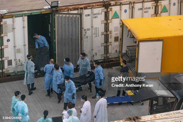 Workers transfer a body of a deceased person at a Mortuary on March 7, 2022 in Hong Kong, China. Hong Kong confirmed more than 29,000 new coronavirus...