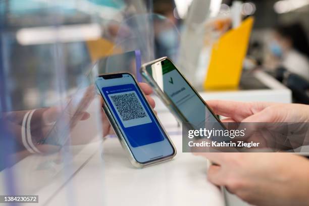 at the airport check-in counter: employee scanning traveler's digital green pass on mobile phone - medical tourism stock pictures, royalty-free photos & images