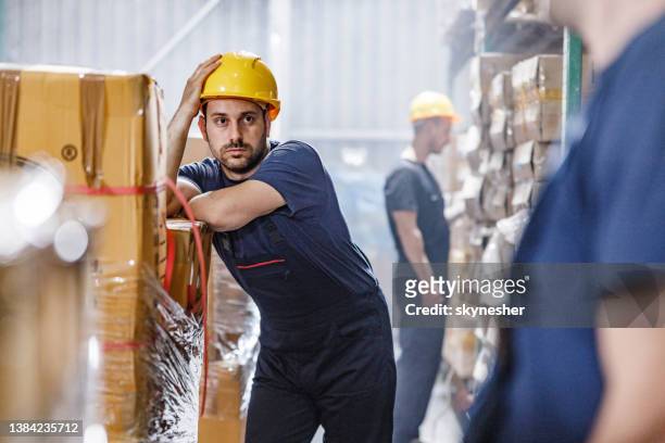 gelangweilter arbeiter, der eine pause im lager macht. - bored worker stock-fotos und bilder