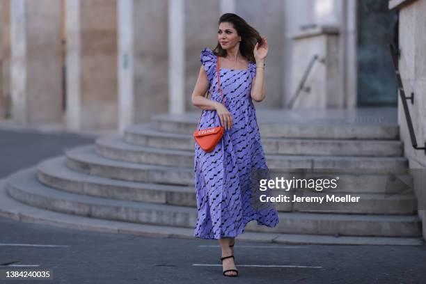 Anna Wolfers wearing a purple maxi dress with pattern via goldigshop.de, a triangle orange Celine logo bag and black heels on March 08, 2022 in...