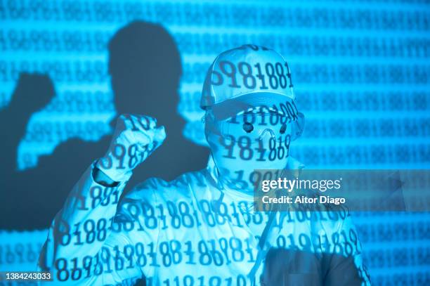 an unrecognisable person with the binary code on his surface with a raised fist. he is claiming something. - poing levé photos et images de collection