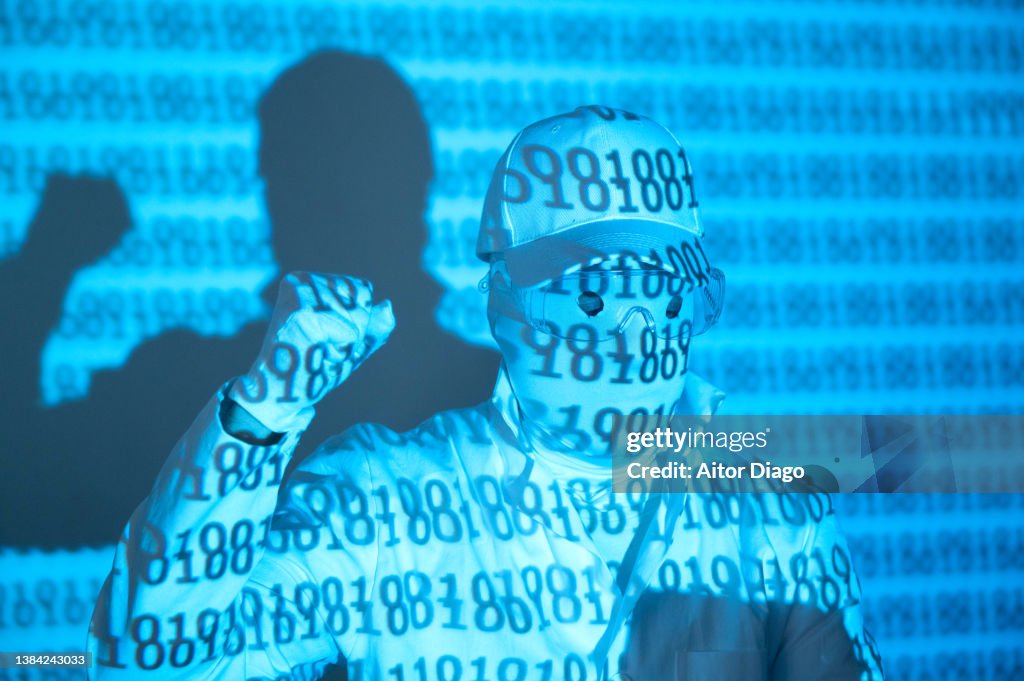 An unrecognisable person with the binary code on his surface with a raised fist. He is claiming something.