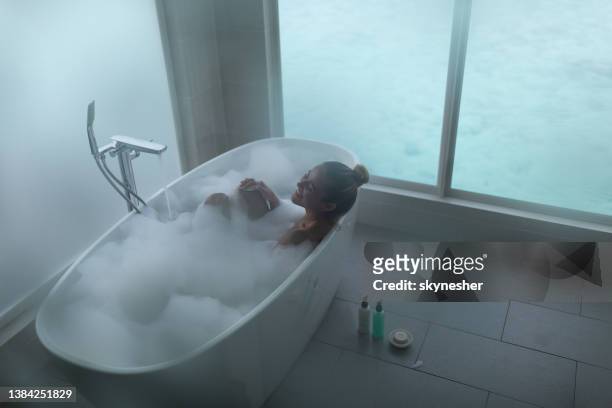 above view of happy woman pampering in bubble bath. - woman bath tub wet hair stock pictures, royalty-free photos & images