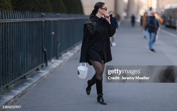 Sarah Lou Falk seen wearing a black sunglasses from Celine, a black shirt dress from Patou, silver earrings, black tights, black cowboy boots and a...