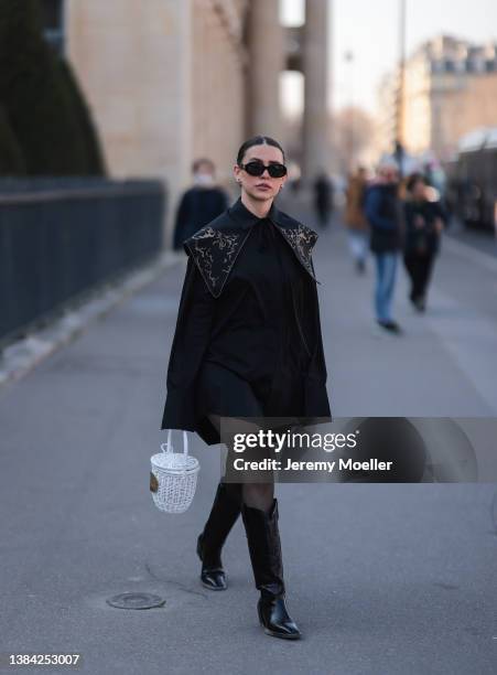 Sarah Lou Falk seen wearing a black sunglasses from Celine, a black shirt dress from Patou, silver earrings, black tights, black cowboy boots and a...