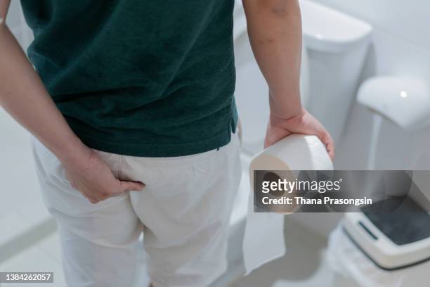 man holding toilet paper roll in bathroom - hemorroide - fotografias e filmes do acervo