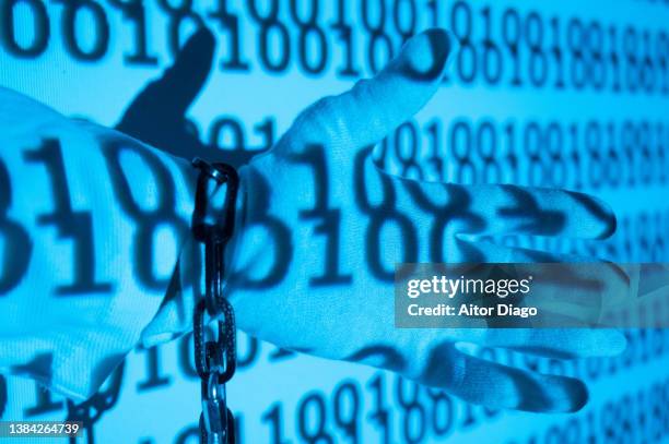 chained hand of a person on an encrypted programming code. - private equity stock-fotos und bilder