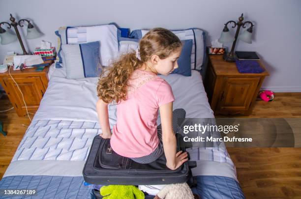 teenager girl trying to close a too full suitcase - teen packing suitcase stock pictures, royalty-free photos & images