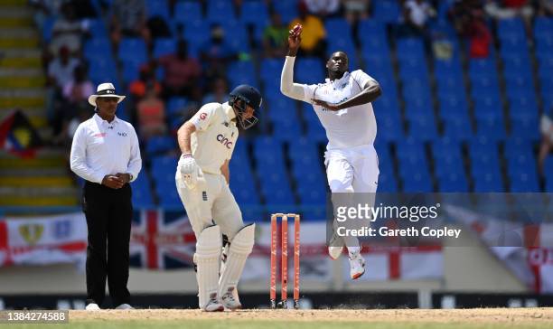 Jason Holder of the West Indies bowls watched by England captain Joe Root during day four of the first test match between West Indies and England at...