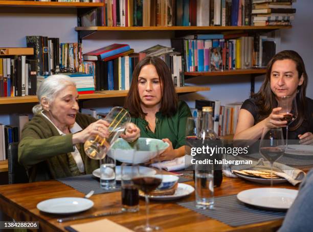 grandmother washing hands at family passover seder - pesach seder stock pictures, royalty-free photos & images