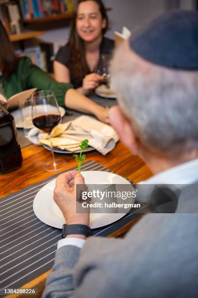 dipping parsley in saltwater at passover seder - seder 個照片及圖片檔